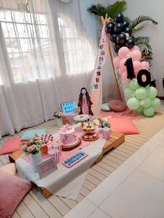 a birthday party with balloons, cake and other items on the floor in front of a window