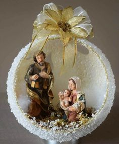 a christmas ornament with a nativity scene on it's side and a gold bow hanging from the top