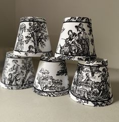 four black and white lampshades sitting on top of a table next to each other