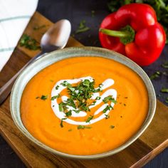 a bowl of carrot soup with garnish on top and spoon next to it