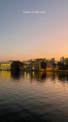 the city is lit up at night on the water's edge, with buildings in the background