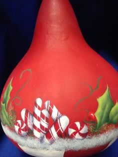 a large red vase with candy canes and holly on it's side, sitting on a blue background