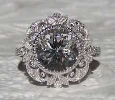 an engagement ring with a large diamond center surrounded by smaller round diamonds on the side