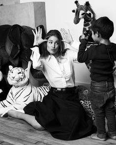 a woman sitting on the floor next to two children with stuffed animals in front of her