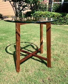 a wooden table sitting on top of a green grass covered field next to a tree