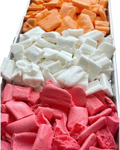 there are many different colored marshmallows in the tray on the table together