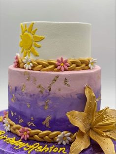 a three tiered cake decorated with flowers and gold leaf decorations on a purple plate