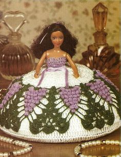 a crocheted doll sitting on top of a table next to some beads and other items