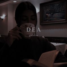 a woman holding a coffee cup and reading a book in a dark room with the words dea on it