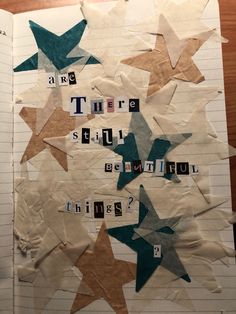 an open notebook with paper stars and words written in them on top of each other