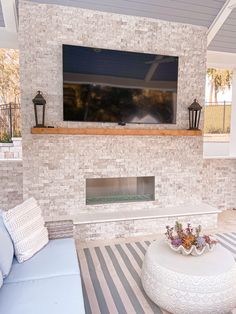 a large flat screen tv mounted to the side of a brick wall above a fireplace