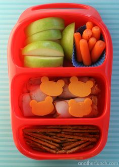 a bento box with carrots, apples, and crackers in the shape of mickey mouse