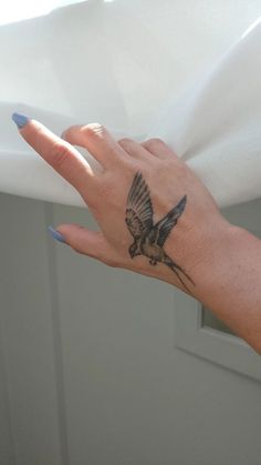 a woman's hand with a bird tattoo on her left wrist and right hand