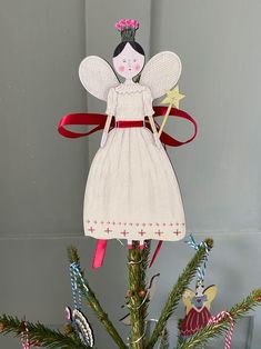 an ornament on top of a christmas tree decorated with ribbons and angel figurines