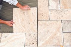 a man laying tile on the ground with his hands and feet resting on top of it