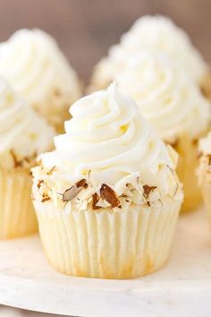 cupcakes with white frosting and nuts on a cake platter, ready to be eaten