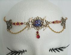 "This beautiful circlet has red glass beads, gold plated accent beads, gold plated chain, brass accent bars, brass pendant with glass dragon's breath fire opal setting, gold plated leaf accents and rhinestones . 20\" long adjustable to 24\" long. Lobster clasp." Antique Jeweled Red Jewelry, Gold Fantasy Jewelry For Wedding, Red Crown Jewelry For Wedding, Gold Fantasy Wedding Jewelry, Handmade Adjustable Headpiece For Masquerade, Gold Fantasy Jewelry For Festivals, Adjustable Red Gothic Jewelry, Gothic Gold Necklace For Wedding, Gold Gothic Necklace For Wedding