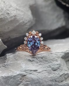 a ring with an oval shaped blue stone surrounded by small white and brown diamonds on top of some rocks