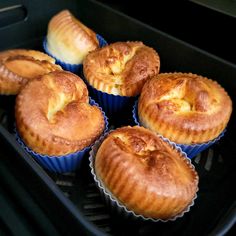 four freshly baked yorkshire puddings sitting in blue paper cups on an air fryer