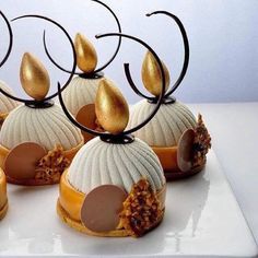 four desserts are arranged on a white plate with gold leaf decorations and chocolate icing