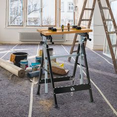 a workbench with tools on the floor in an empty room next to a ladder