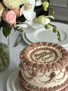 a cake sitting on top of a white plate next to a vase filled with flowers