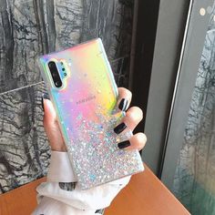 a woman holding up her phone case with glitter on it