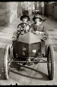 two children are riding in an old fashioned car