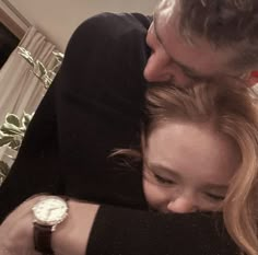 a man and woman hugging each other with a watch on their arm in front of them