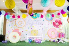 a birthday party with donuts, balloons and streamers hanging from the ceiling in front of a backdrop