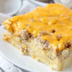 a piece of casserole on a white plate with cheese and meat toppings