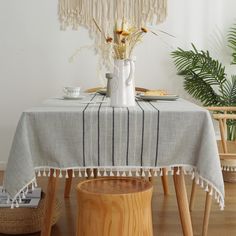 a table with a white vase filled with flowers on top of it next to a wooden stool