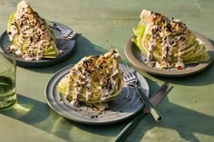 two plates filled with lettuce covered in toppings next to a glass of water