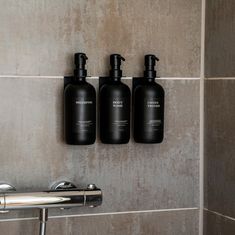 three black bottles are hanging on the wall