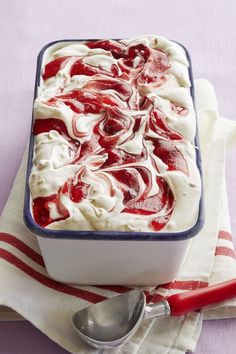 a red and white dessert in a blue dish on a pink tablecloth with spoons