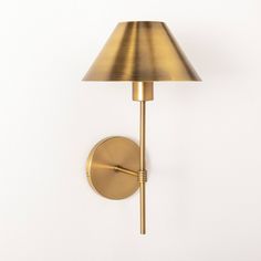 a wall light with a gold shade on it's side and a white background