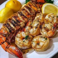 a white plate topped with shrimp and lemon wedges