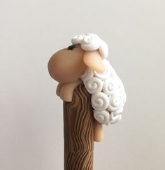 a small toy sheep on top of a wooden stick with white hair and black eyes