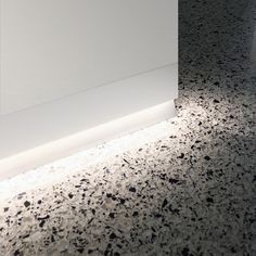 a white wall with black and white speckles on the floor next to it