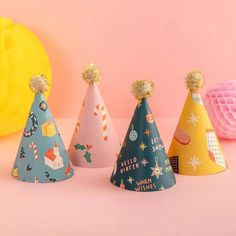 three party hats are lined up against a pink background