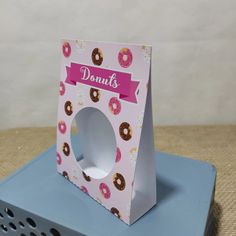 a pink box with donuts on it sitting on top of a blue tablecloth