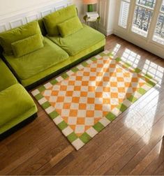 a green couch sitting on top of a hard wood floor