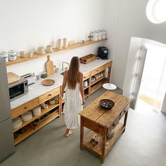 a woman standing in a kitchen next to a table with plates and bowls on it