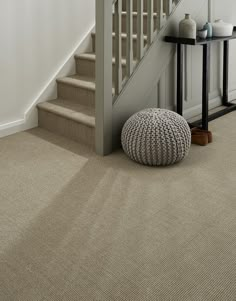 a carpeted entryway with stairs and a round rug on the floor next to a table