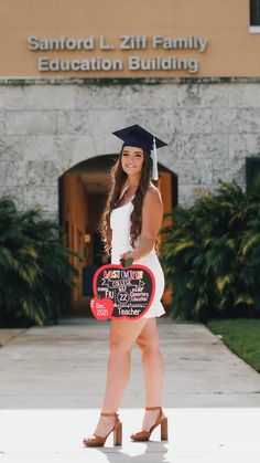 a woman in a graduation cap and gown holding a sign that reads stanford l ziff family education building