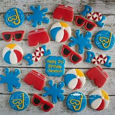 decorated cookies are arranged in the shape of hats, sunglasses and beach balls on a wooden table