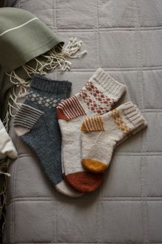 three pairs of socks laying on top of a bed