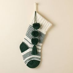 a green and white stocking hanging on the wall with two tasseled balls