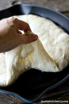 a person is kneading dough into a skillet