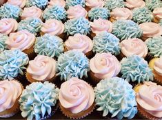 cupcakes with blue and pink frosting are arranged in a box on the table